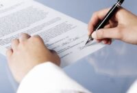 Close up of woman signing a legal document or contract, blank background.