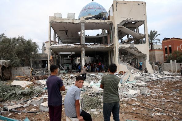 Palestinian stare at a mosque-turned-shelter in Deir al-Balah in the central Gaza Strip, heavily damaged in an Israeli strike during the night of October 6, 2024, amid the ongoing war between Israel and the Palestinian Hamas movement. Gaza's civil defence agency said on October 6 that an Israeli strike on the mosque-turned-shelter in central Deir al-Balah killed 21 people, while Israel's military said it had targeted Hamas militants. (Photo by BASHAR TALEB / AFP)