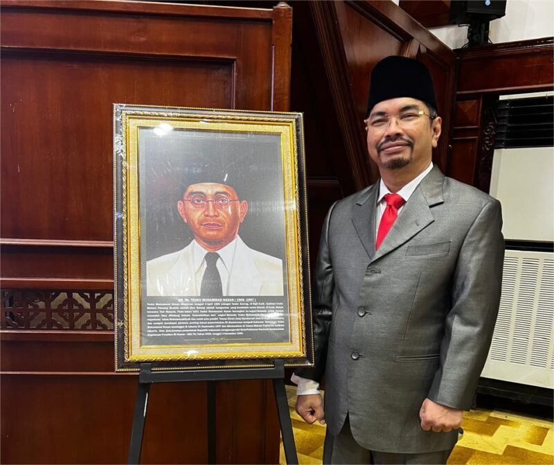 Ir. Teuku Iskandar Shah berfoto di depan potret Dr. Mr. Teuku Haji Moehammad Hasan.